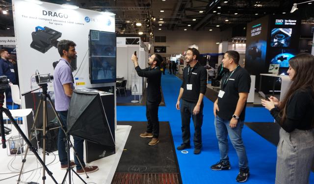 Visitors taking pictures of the image on screen at the IACTEC stand.